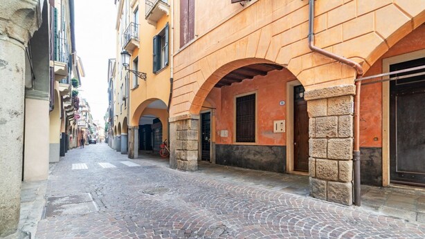 Una calle empedrada con edificios que presentan arcos y columnas de piedra.