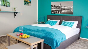 A modern bedroom with a bed, bedside table, and a small table with fruit and glasses. - ORCA Hotel am Elbschloss (Dresden)