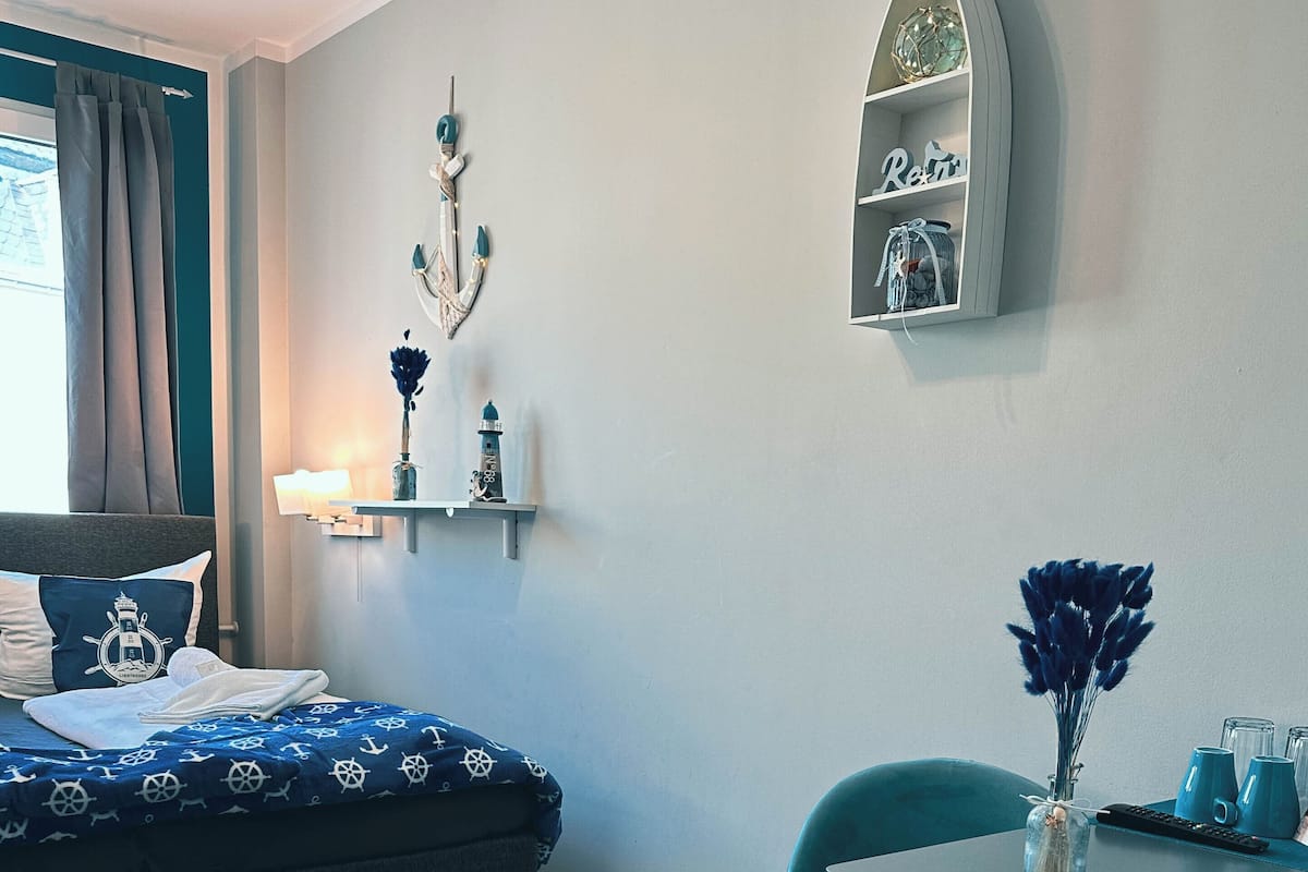 Une pièce comprenant un lit, un bureau et une chaise. On y trouve une étagère avec des objets décoratifs et une horloge.