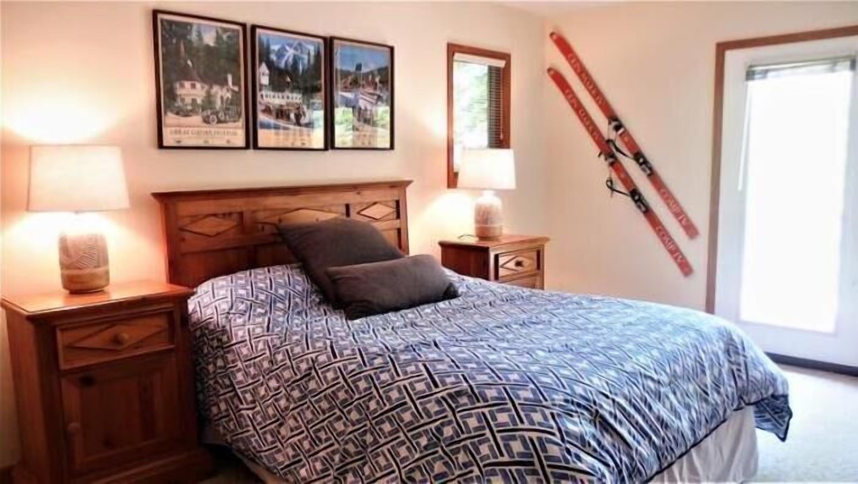 Une chambre à coucher comprenant un lit, deux tables de chevet, une tête de lit et trois tableaux encadrés accrochés au mur.