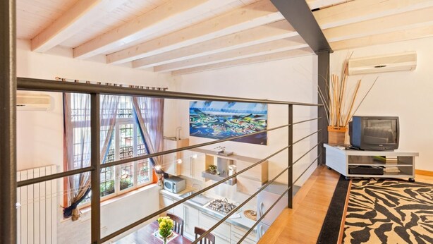 A modern interior with a dining area, kitchen, and a large painting on the wall. - GuestHost - Lovely loft apartment just 350m from Lodi M3 stop (Milano)