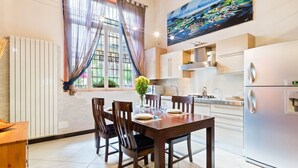 A modern kitchen with a dining area, large windows, and a painting on the wall. - GuestHost - Lovely loft apartment just 350m from Lodi M3 stop (Milano)