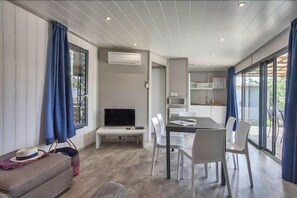 Una sala de estar moderna con un televisor de pantalla plana, una mesa de comedor con sillas y un sofá.