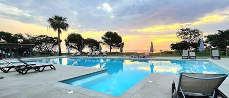 Una piscina al aire libre de temporada, sombrillas