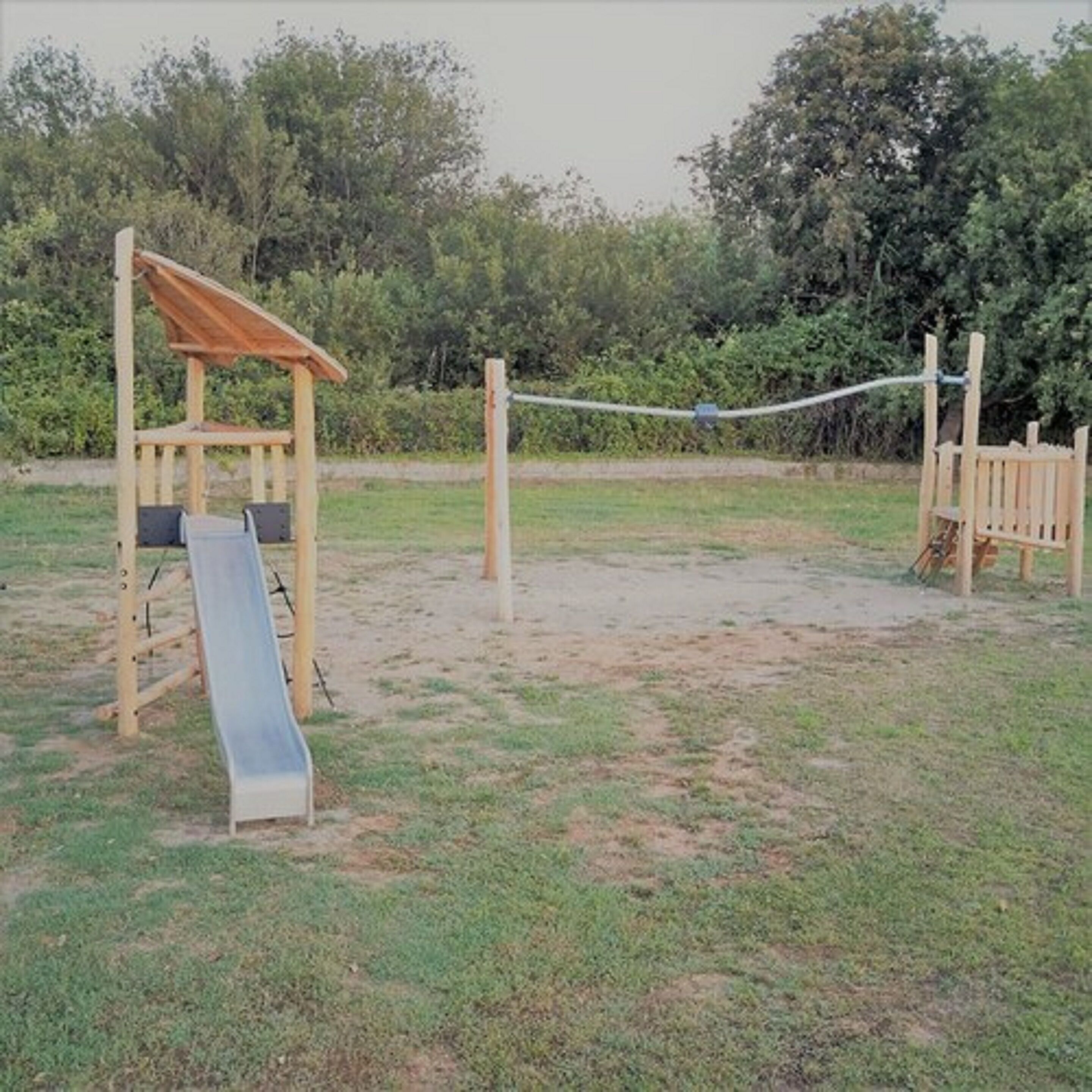 A playground with a slide, climbing structure, and swings.