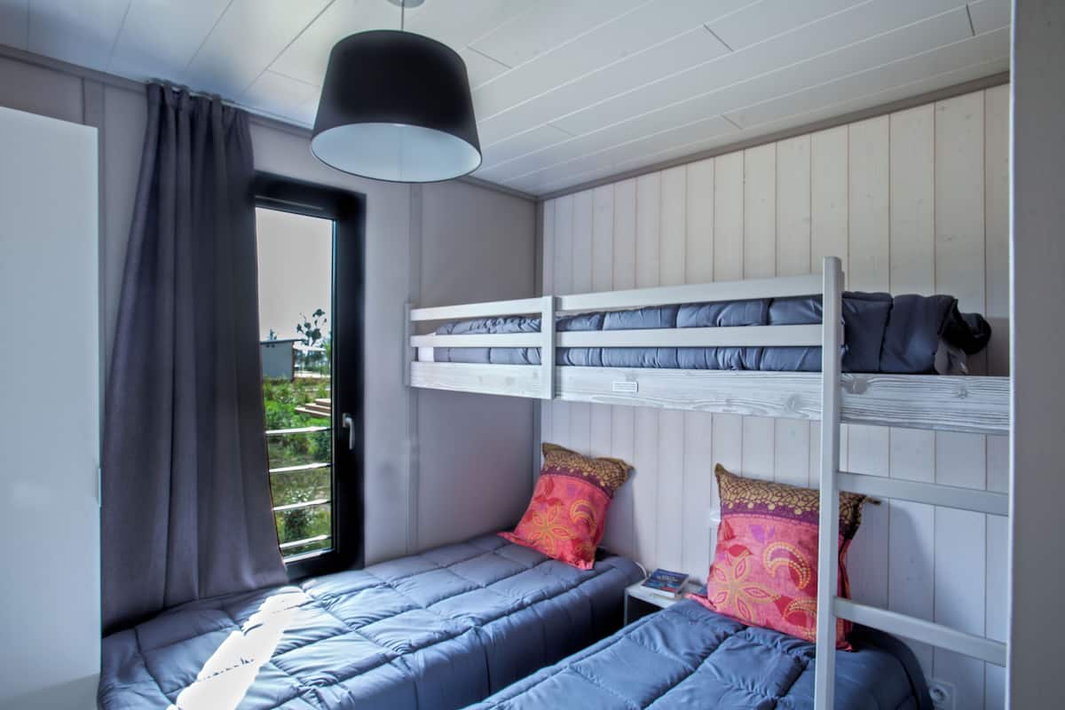 Dormitorio con literas, ventana y lámpara colgante.