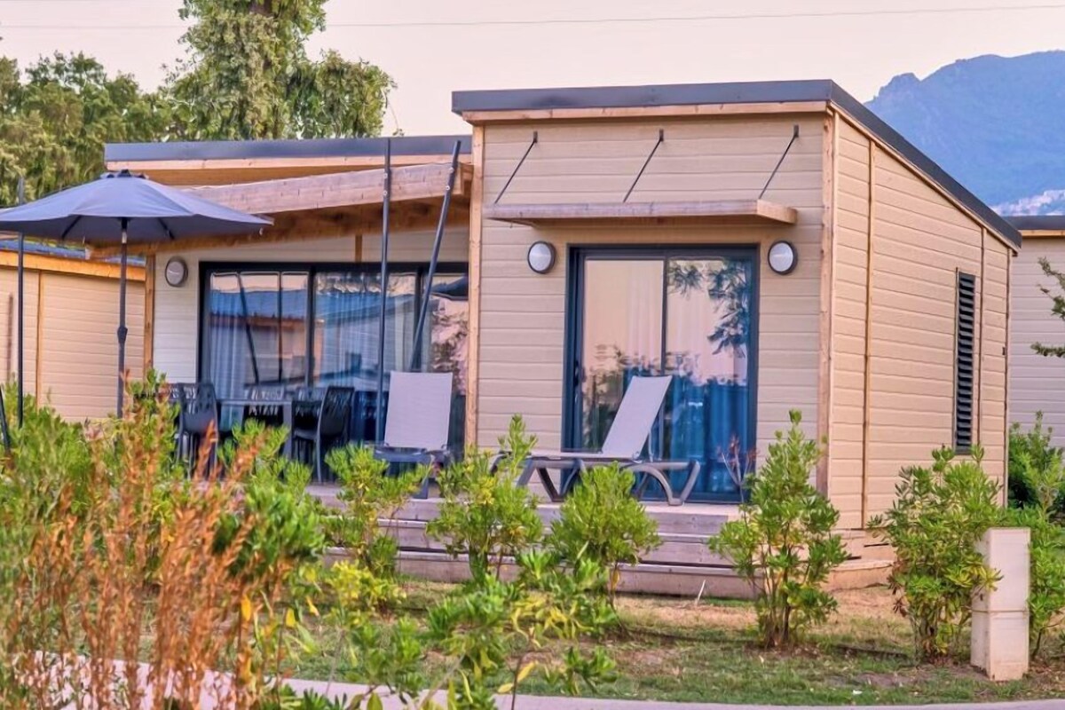 Un bâtiment moderne à deux étages, doté d’un toit plat, de grandes fenêtres et d’un patio avec des espaces de détente en plein air.