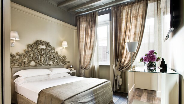 A hotel room with a large bed, a glass desk, and a mirror.