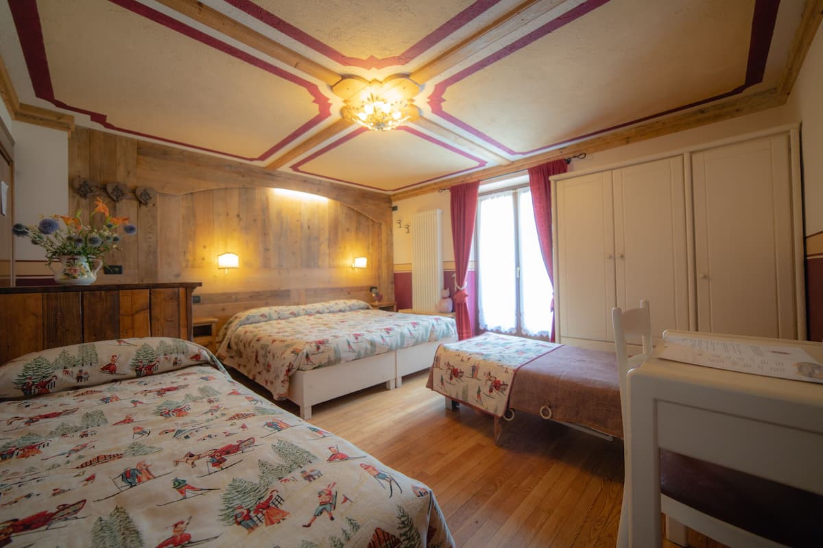 Una habitación acogedora con dos camas, techo de madera y una pequeña mesa con lámpara.
