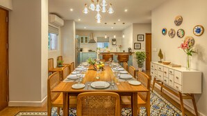 A dining area with a wooden table set for six, surrounded by wicker chairs. - amã Stays & Trails, Braganza House - Goa (Candolim)