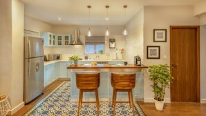 A modern kitchen with a central island, stainless steel appliances, and light blue cabinetry. - amã Stays & Trails, Braganza House - Goa (Candolim)