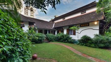 A traditional building with a tiled roof, surrounded by lush greenery and a well-maintained garden.