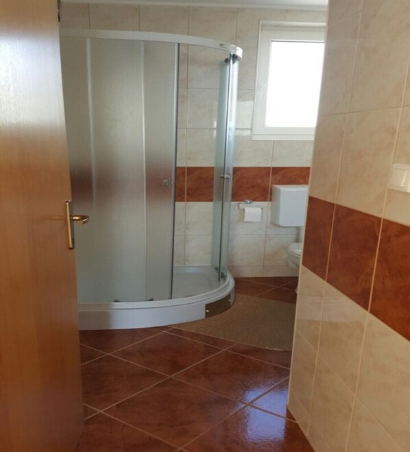 A bathroom with a glass shower enclosure, a toilet, and a towel rack.