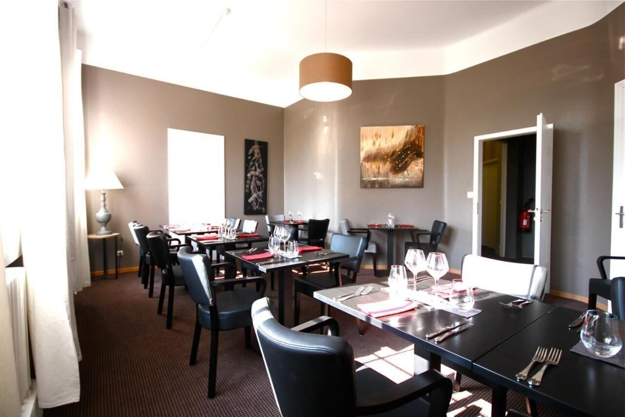 A dining area with tables set for two, chairs, and a lamp.