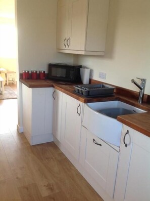Eine Küche mit weißen Schränken, einer Mikrowelle und einem Spülbecken.