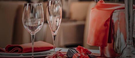 A dining table with two wine glasses, a red napkin, and two gift boxes.