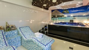 Un espacio de spa moderno con un amplio jacuzzi, un rincón de descanso con piso de mosaico y un mural de una playa tropical.