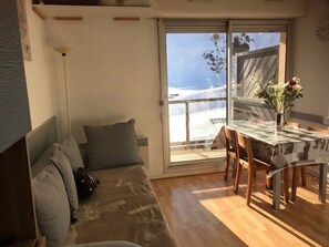 Relax in a compact living space with a comfortable sofa, dining table, and sliding glass door offering a view of the surrounding landscape.