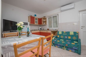 Uma cozinha compacta com mesa, cadeiras, sofá e televisão.