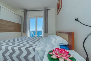 A hotel room with a bed, a view of the balcony, and a lotus flower decoration. - Apartment Zlatica (Crikvenica)
