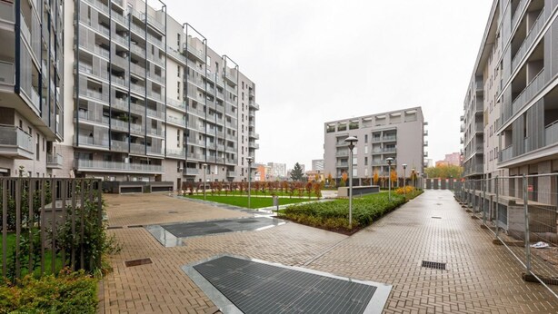 A modern apartment complex with multiple floors, a central courtyard with a water feature, and a paved walkway. - GuestHost - Bright apartment included in a building of very recent construction (Milano)