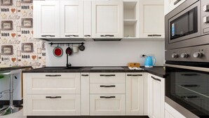 A kitchen with white cabinets, a black countertop, a double oven, and a kettle. - GuestHost - Bright apartment included in a building of very recent construction (Milano)