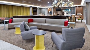 Un moderno vestíbulo de hotel con una zona de estar que incluye sofás y sillones, un bar y un comedor.