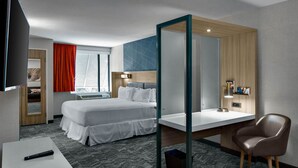 Habitación de hotel con cama, escritorio, silla y televisor.