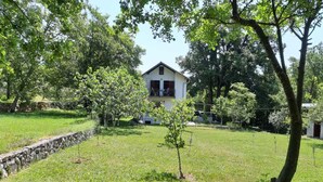 A house with a balcony, surrounded by a grassy yard and trees. - Holiday House Stipe (Bakar)