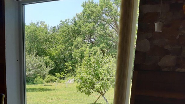 A room with a large window overlooking a grassy area with trees. - Holiday House Stipe (Bakar)