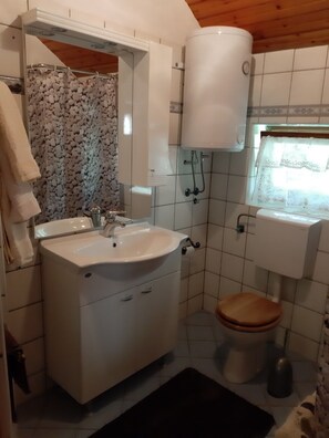 A bathroom with a white sink, a wooden toilet, a white toilet paper holder, and a white toilet paper roll. - Holiday House Stipe (Bakar)