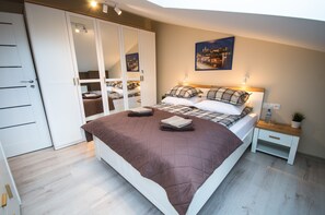 A bedroom with a large bed, a wardrobe, a bedside table with a lamp, and a painting on the wall.