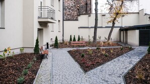 A courtyard with a paved walkway, benches, and a small garden area with plants and mulch. - Old Town Vistula Premium Apartments (Kraków)