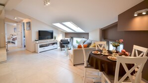 A modern living room with a dining area, a television, and a skylight. - Old Town Vistula Premium Apartments (Kraków)
