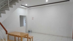 Una habitación con una mesa de madera y un banco, una escalera y suelo de baldosas blancas.