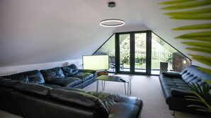 A modern living room with a black leather sofa, a small coffee table, and a TV. - The Old Bushmills Barn (Bushmills)