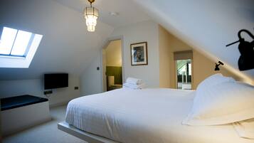 A bedroom with a bed, a flat-screen TV, a desk, a chair, a window, and a ceiling light.
