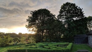 A garden with a maze, stone wall, and a wooden bench. - The Old Bushmills Barn (Bushmills)