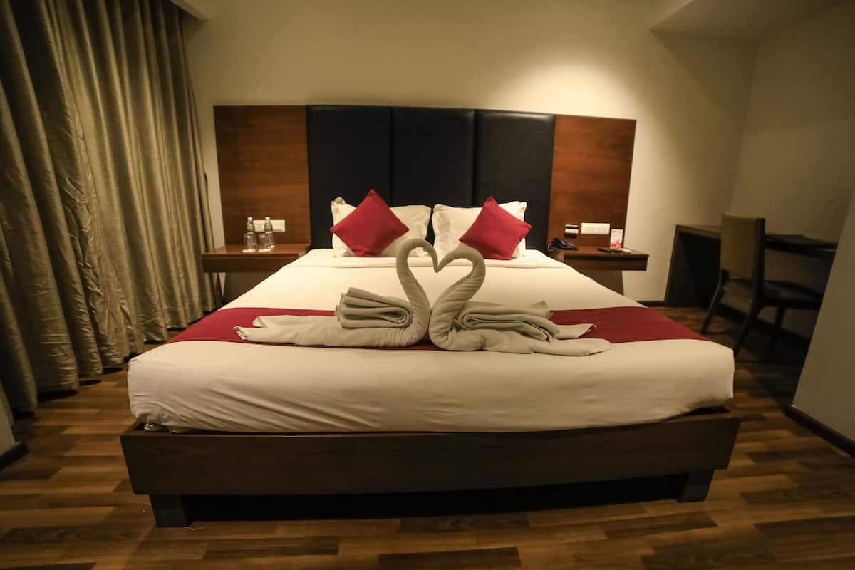 Habitación de hotel con una cama grande, cabecero de madera y un escritorio con silla.