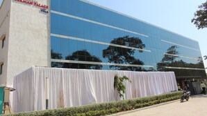 A modern hotel with a glass facade and a white curtain covering the entrance. - Hotel German Palace (Gandhinagar)
