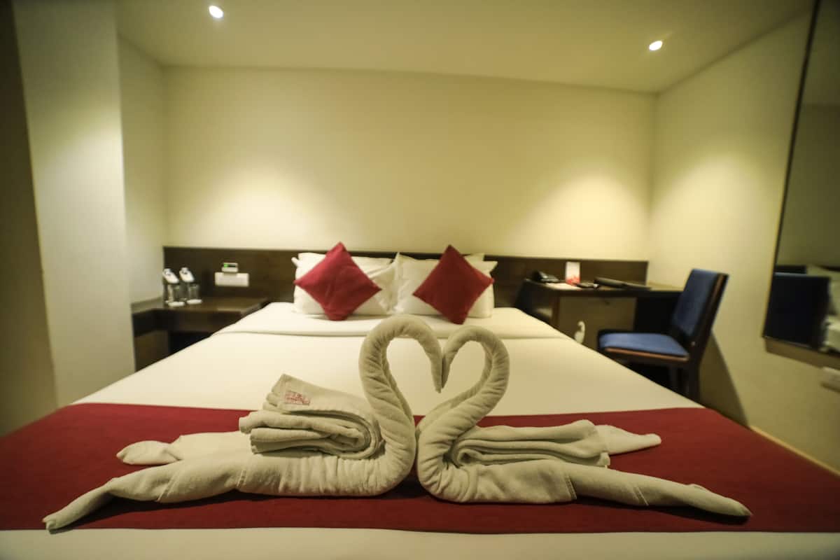 Una habitación de hotel con una cama bien hecha, un escritorio con una silla y un espejo en la pared.