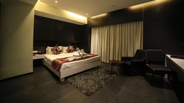 A modern hotel room with a large bed, a desk, and a chair. - Hotel German Palace (Gandhinagar)