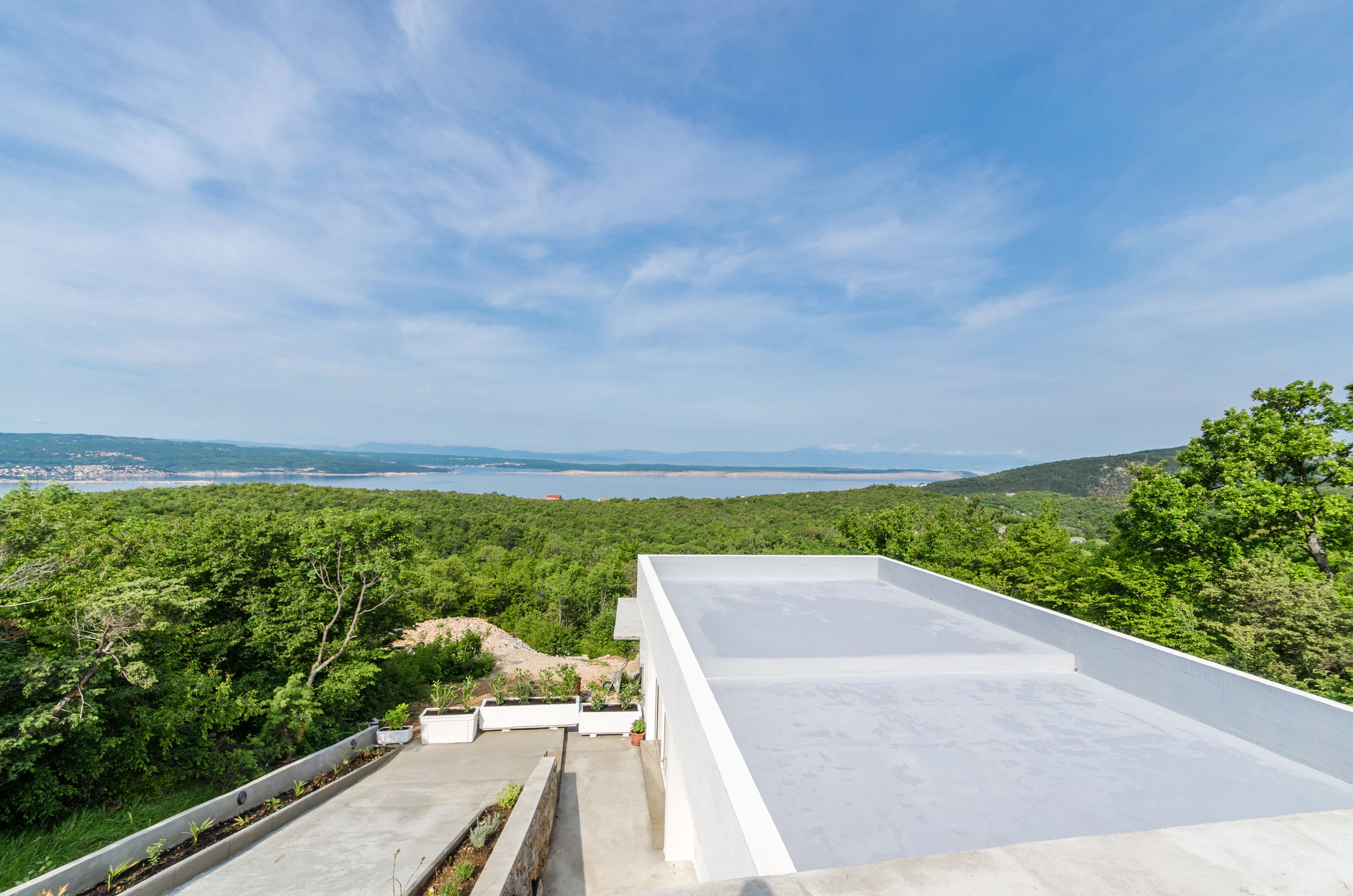 A rooftop terrace with a clear view of the surrounding landscape, including distant hills and a body of water.