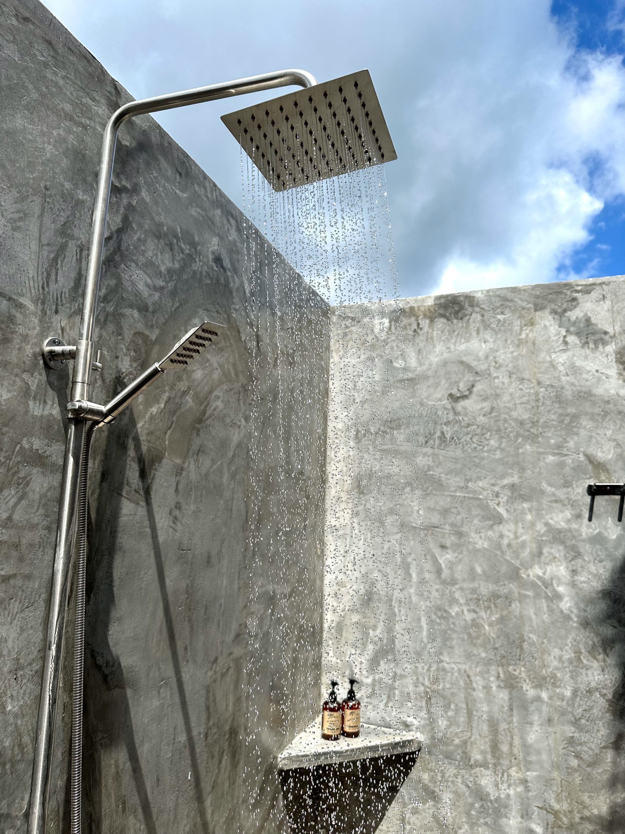 Une douche dotée d’un pommeau de douche imitant une pluie fine, d’un pommeau de douche à main et d’un robinet mural.