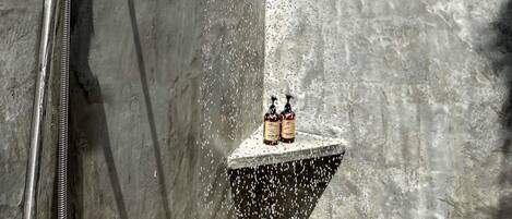 Une douche dotée d’un pommeau de douche imitant une pluie fine, d’un pommeau de douche à main et d’un robinet mural.