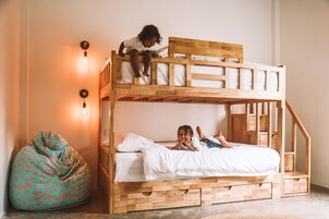 A bunk bed with two children, a bean bag chair, and wall-mounted lights.