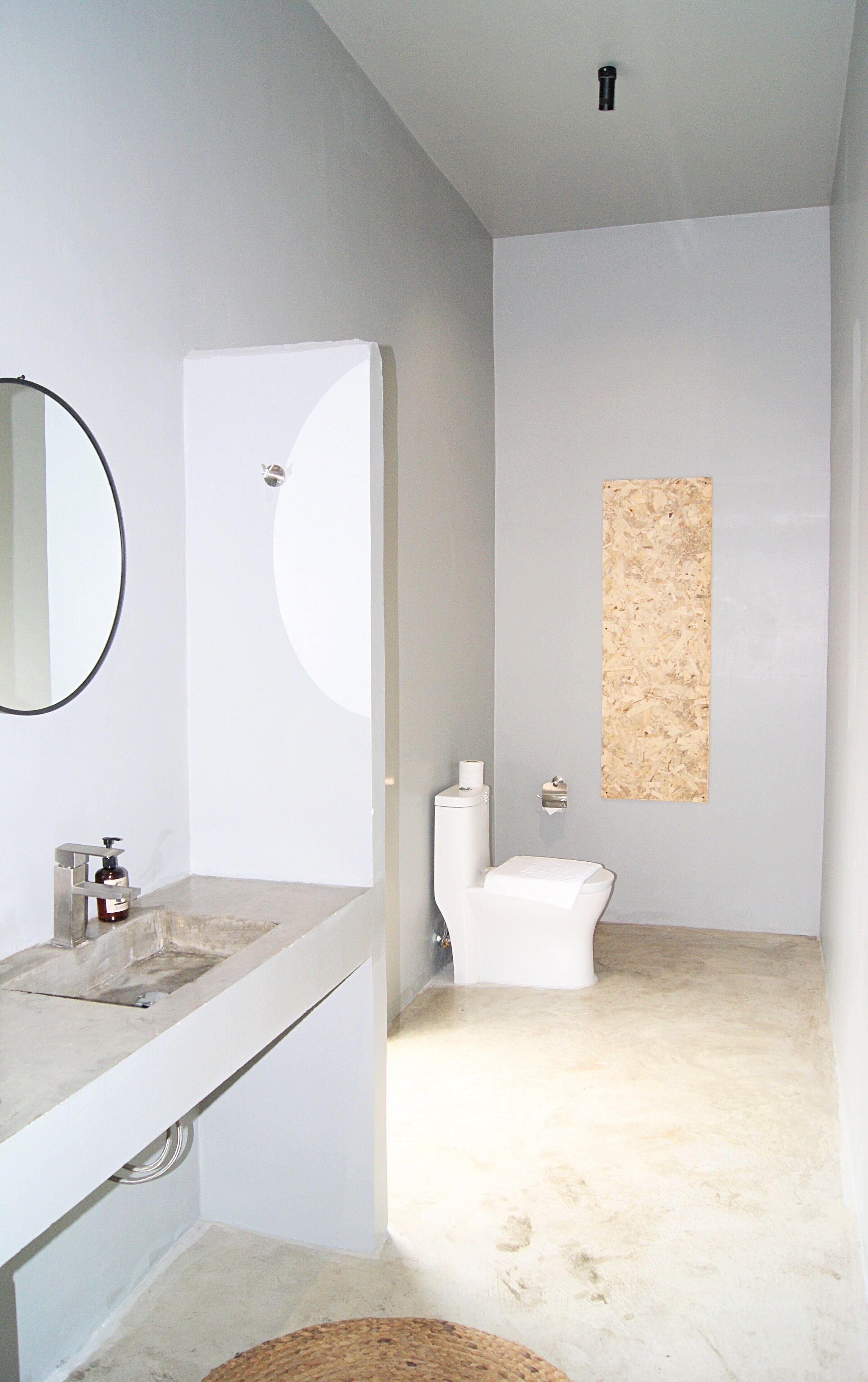 A modern bathroom with a white sink, mirror, and toilet.