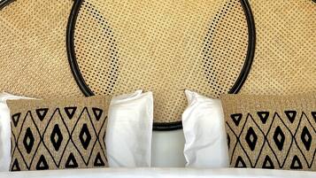 A bed with a rattan headboard and patterned pillows.