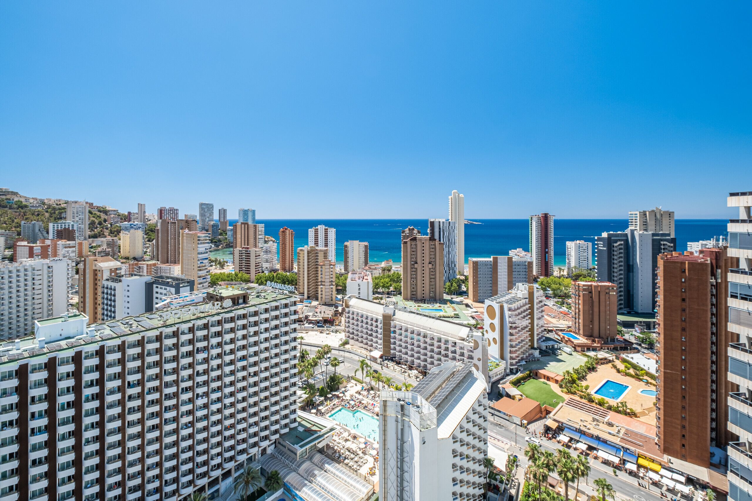 Un hotel di grandi dimensioni con numerosi piani, una piscina sul tetto e vista sull'oceano.