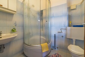 A bathroom with a glass-enclosed shower, a sink, and a toilet. - Apartment Heidy (Crikvenica)